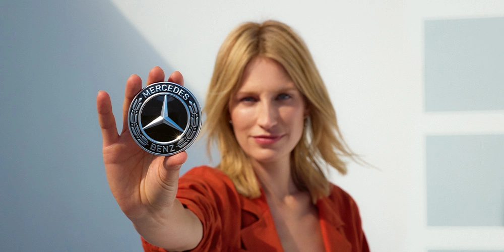Foto van een mevrouw die het embleem van Mercedes-Benz krachtig vasthoudt